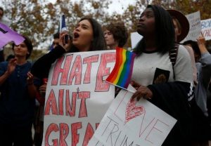 In the foreground, two women hold protest signs at a rally.