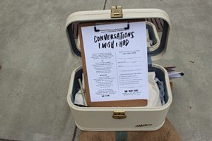 An open suitcase holds a clipboard with a paper reading 'Conversations I wish I had'