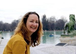 A picture of Micah Perks leaning forward. She has blonde hair and a yellow sweater.