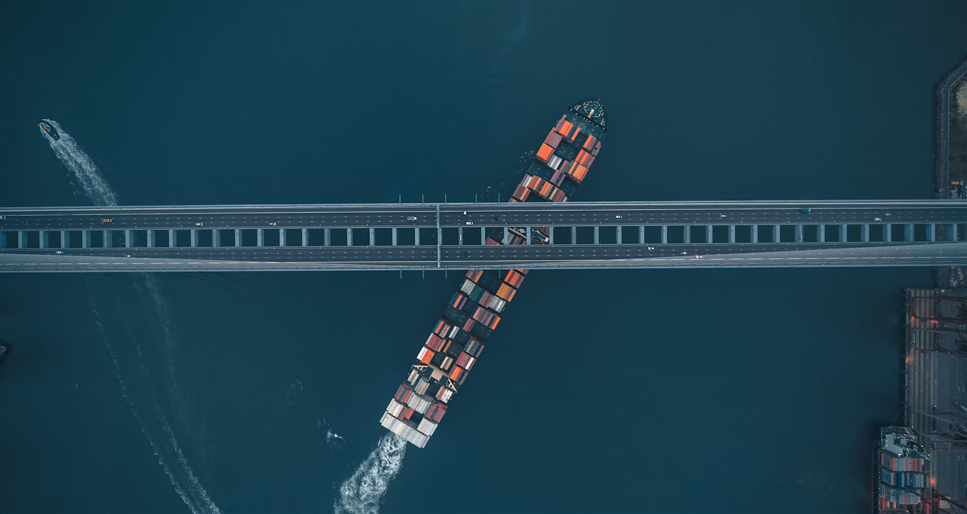 Chris Chen cargo ship passing beneath a bridge